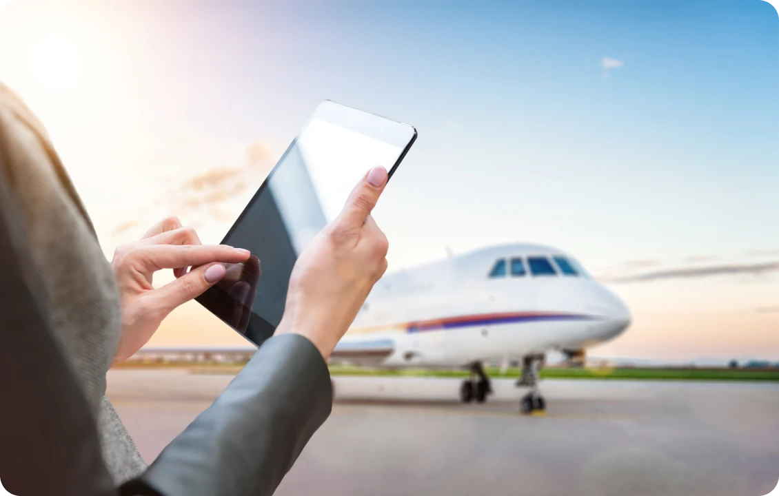 Person using tablet near airplane on runway.